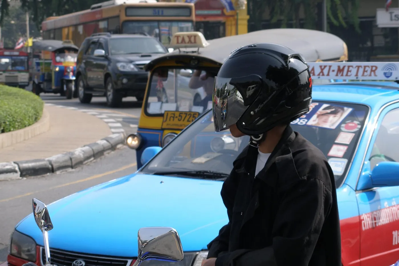 The street the building stands on, a food cart, a motorbike, marigold garlands at a stall.