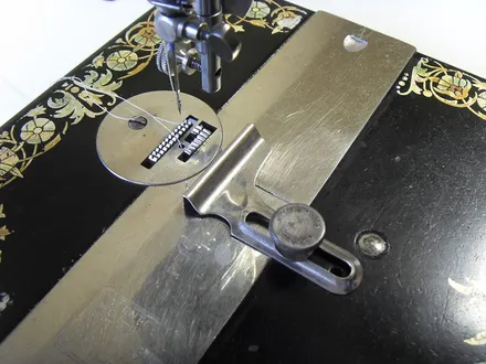 Hands guiding fabric under the needle of an industrial sewing machine. No faces.